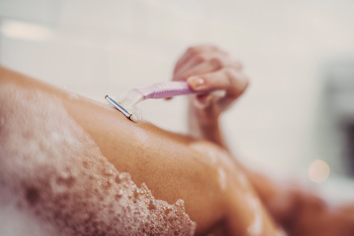 Woman shaving her legs in a bathtube.