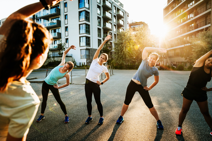 An urban fitness group for women warming up before a run through the city together.